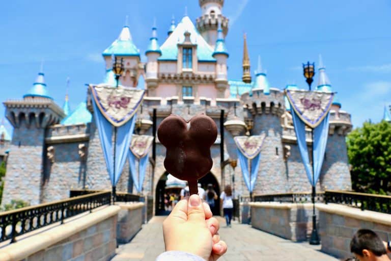 A Mickey ice cream bar in front of the castle on a bright sunny day