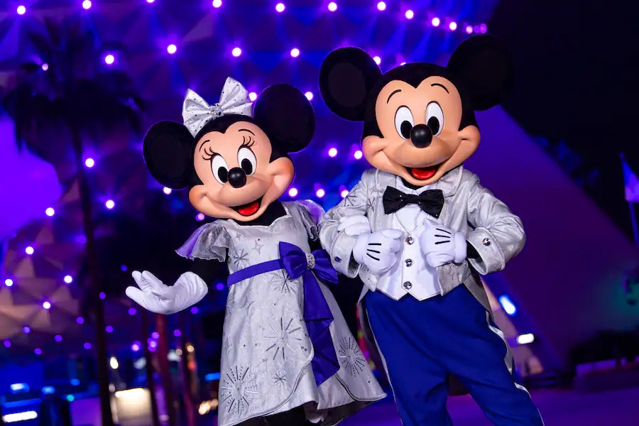 Mickey and Minnie in platinum outfits in front of Spaceship Earth
