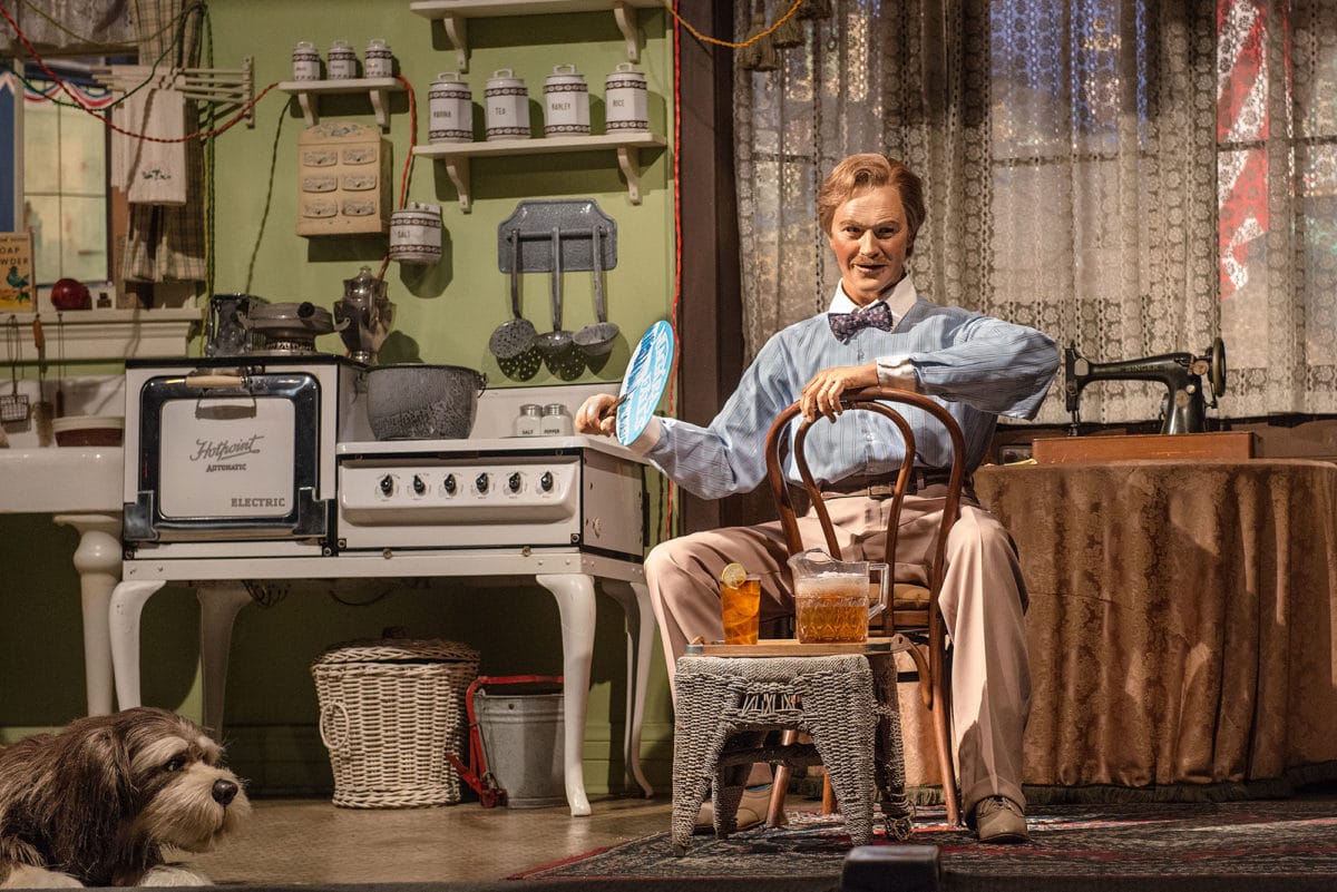 A man in vintage attire sits in a retro kitchen, evoking the spirit of Disney's Carousel of Progress.